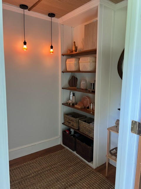 Shelves of woven baskets and rolled towels under warm pendant bulbs