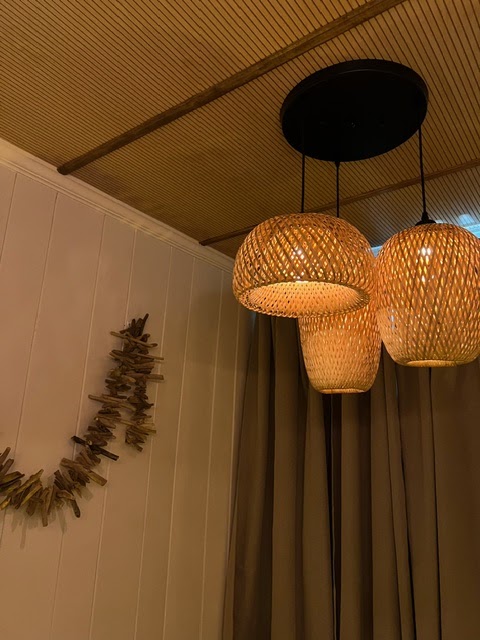 Woven pendant lamps glowing against a driftwood garland