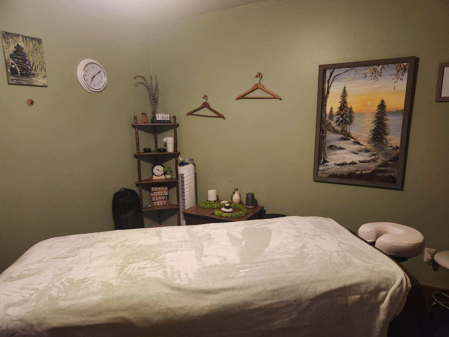 A treatment room with sage green walls and a made-up massage table