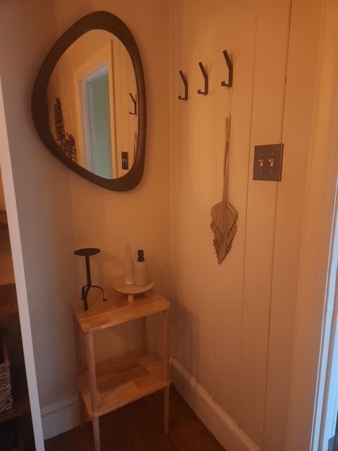 A mirror and small side table in the entry, softly lit